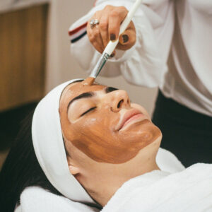 Beauty therapist applying face mask to woman