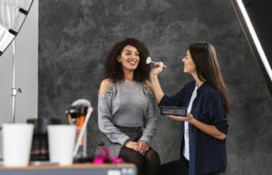 beauty therapist applying makeup to woman