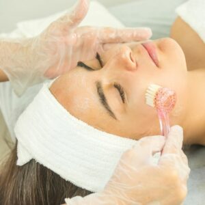 skin therapist applying facial scrub to a woman's face