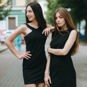 Two women with long hair wearing black dresses