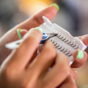 Hands holding a small container of lash extensions