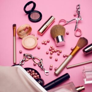 Makeup items scattered on a pink background