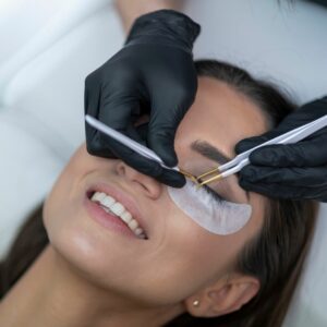 Lash technician's hands applying lashes to woman's face