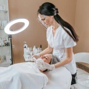 Woman giving another woman a facial treatment