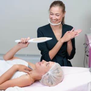 Woman checking her face after beauty treatment, with a beauty therapist standing in the background