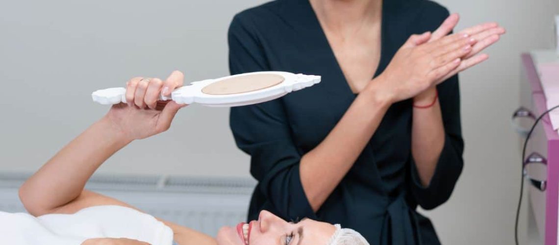Woman checking her face after beauty treatment, with a beauty therapist standing in the background