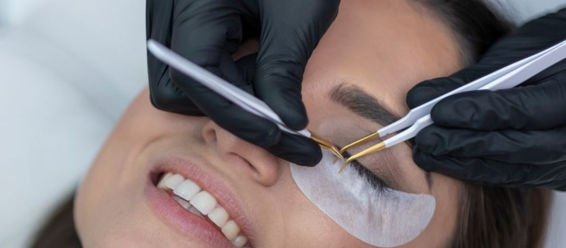 Lash technician's hands applying lashes to woman's face