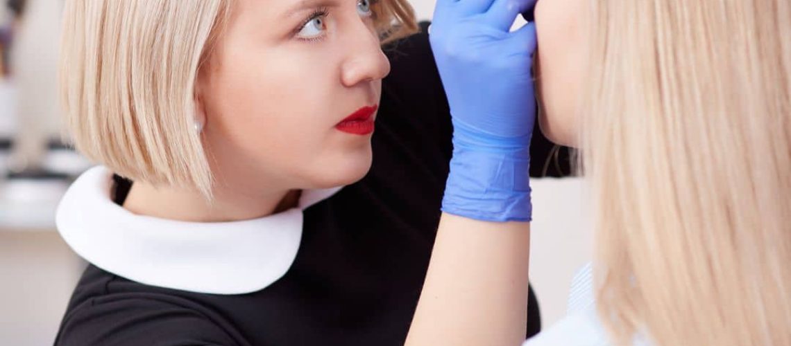 Eyebrow technician working on a woman's brows