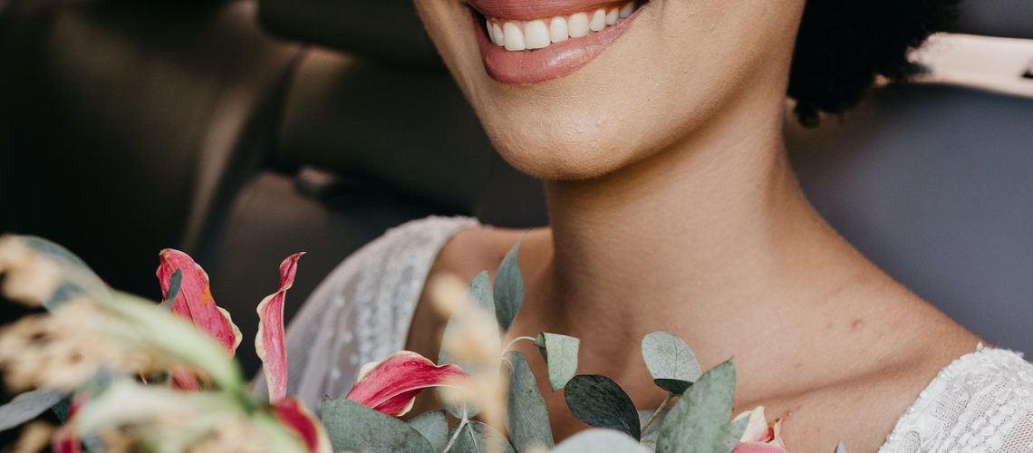 Woman wearing makeup in a car with a bouquet