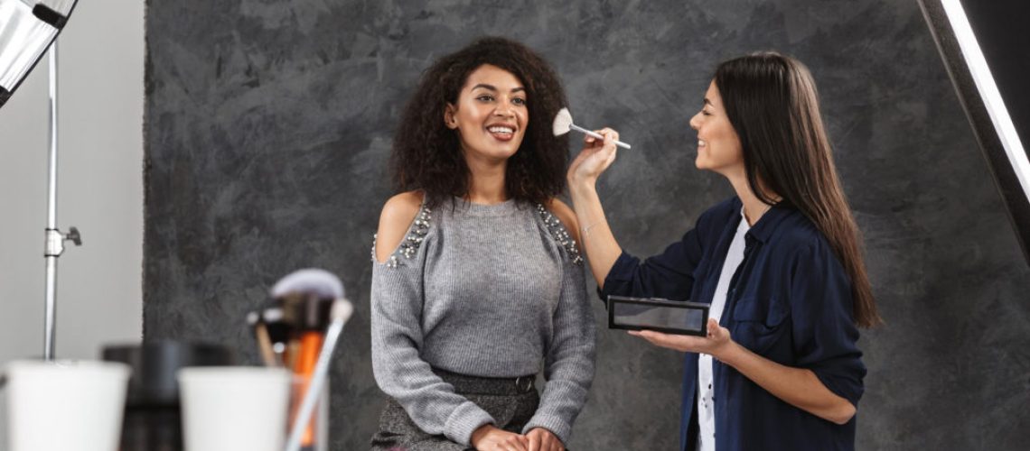 beauty therapist applying makeup to woman