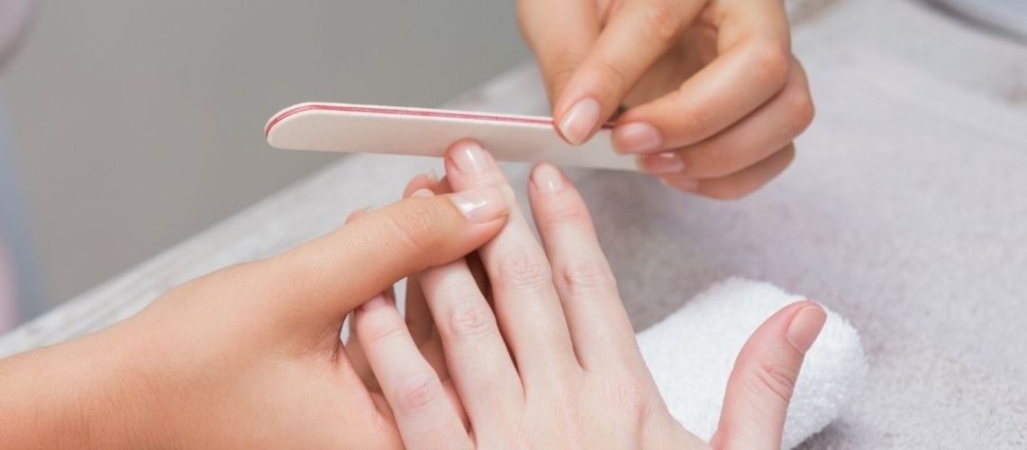 Nail tech filing a woman's nails