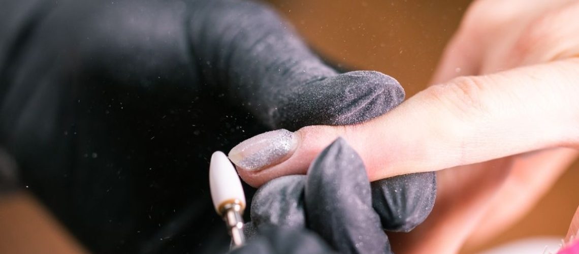 Nail tech making adjustments to a nail