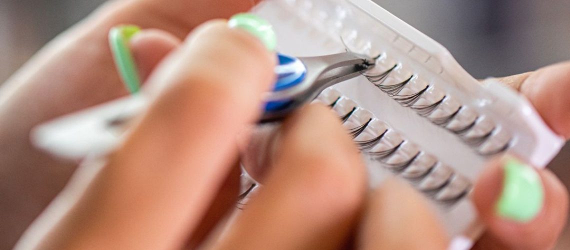 Hands holding a small container of lash extensions