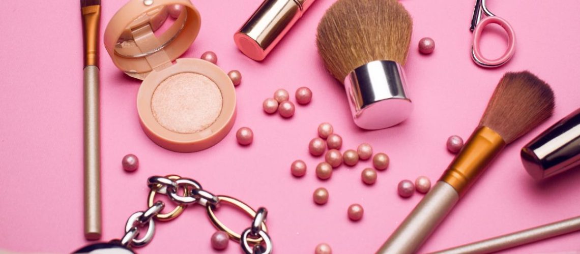 Makeup items scattered on a pink background